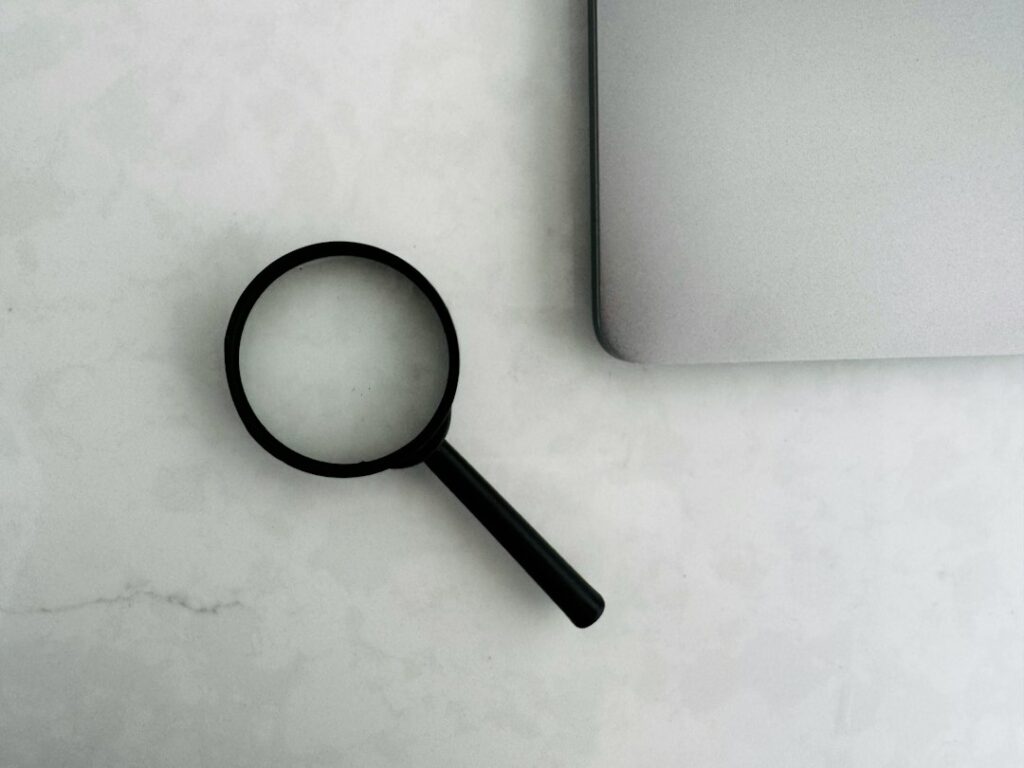Lente d'ingrandimento accanto a un computer per la ricerca e deindicizzazione